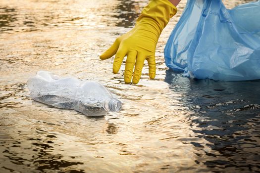 Volunteer cleaning river trash pick up litter picking. Picking up garbage water plastic nature. Cleaning trash beach waste plastic PET bottle plastic pollution. Collecting trash. Collect garbage beach