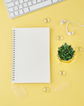 Blank notepad page in bullet journal on bright yellow office desktop. Top view of a modern bright table with notebook, minimalism. Mock up, copy space, concept for diary, vertical