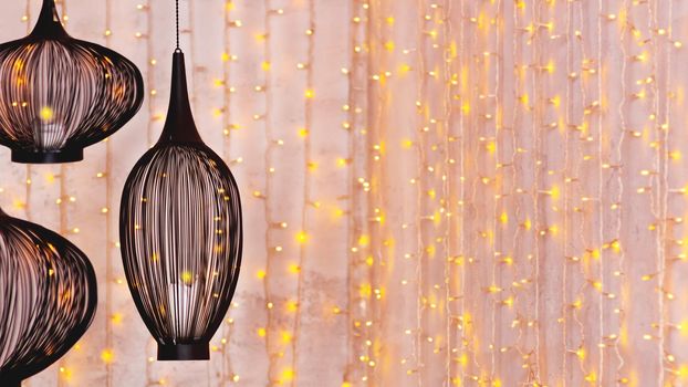 Black ethnic lanterns on background with light bulbs. Eastern lamps on festive Ramadan background. Horizontal banner with copy space.