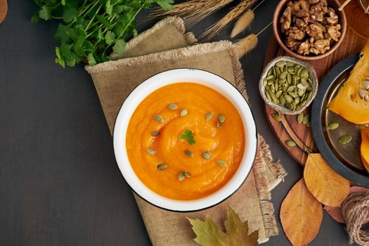 healthy and vegetarian creamy soup with pumpkin seeds and nuts, copy space, autumn leaves