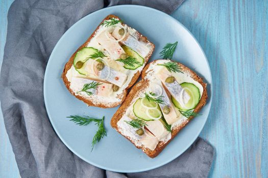 Herring smorrebrod - traditional Danish sandwiches. Black rye bread with herring on dark blue table, top view