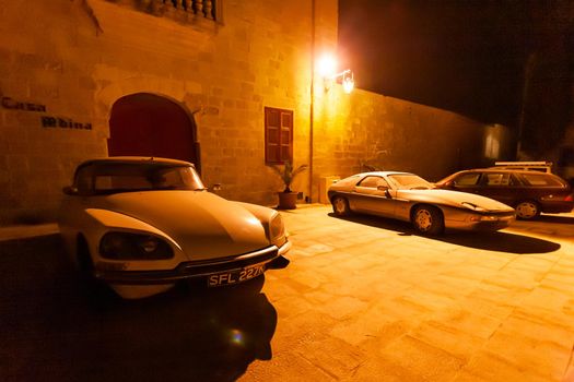 MDINA, MALTA - February 19, 2010. Old timer cars parked near stony buildings of Mdina, ancient capital of Malta.