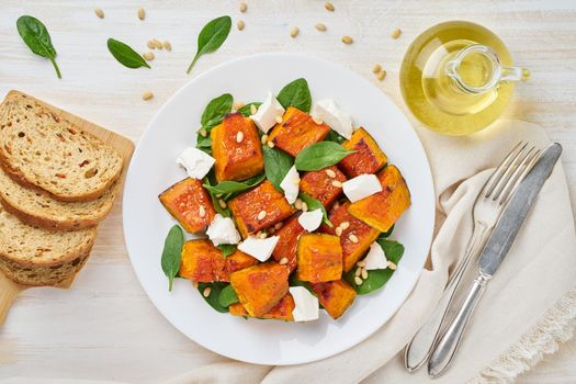 Salad with roasted pumpkin, feta cheese, spinach, nuts with honey and seasonings, top view