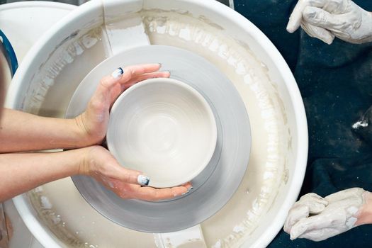 Woman making ceramic pottery, four hands close-up, focus on a potters, palms with pottery, concept for workshop and master class. Creative hobby concept. Earn extra money, side hustle