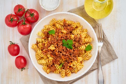 Bolognese pasta. Fusilli with tomato sauce, ground minced beef. Traditional italian cuisine. White wooden table. Top view
