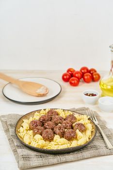 Swedish meatballs with fusilli paste on white wooden table, copy space, side view.