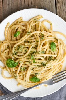 Pesto spaghetti pasta with basil, garlic, pine nuts, olive oil. Vertical. Rustic old table