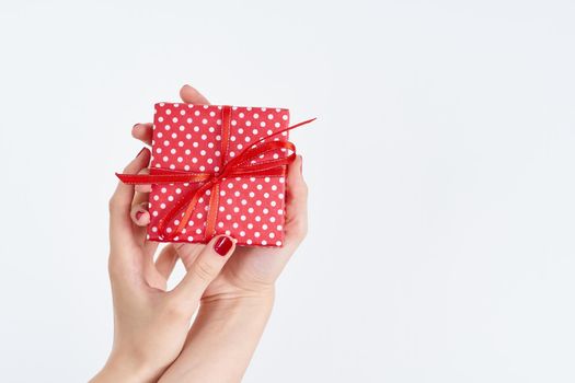 beautiful woman hands holding a red present with ribbon, hands with red nail polish gloss shine, concept on white background copy space