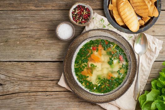 Rustic chicken soup with garnish, parsley, vegetables, homemade dish on the old dark table, top view, copy space.