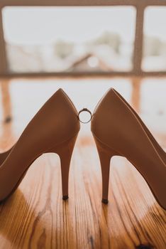 a ring between two women's high heel shoes. Morning of the bride