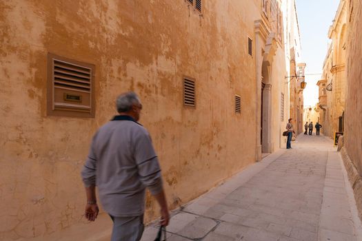 MDINA, MALTA - February 18, 2010. Local old men on narrow street of Mdina, old capital of Malta. Stone buildings with old fashioned doors and balconies.