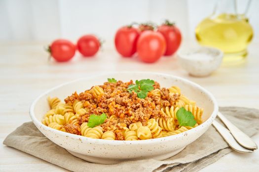 Bolognese pasta. Fusilli with tomato sauce, ground minced beef. Traditional italian cuisine. White wooden table. Side view