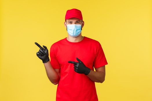 Express delivery during pandemic, covid-19, safe shipping, online shopping. Handsome courier in red uniform, protective medical mask and gloves, provide shipping information, freight logistics.