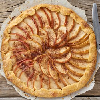 Apple pie, galette with fruits, sweet pastries on old wooden rustic table, top view