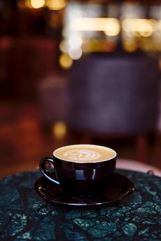 A Cup of cappuccino with foam on a marble table in a cozy little cafe. Drink with vegetable milk, oatmeal, coconut, vertical