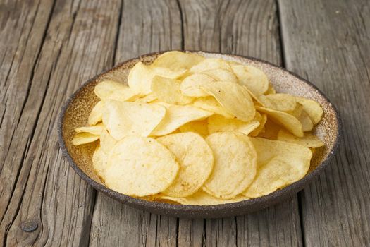 crisp in bowl, wooden background, closeup