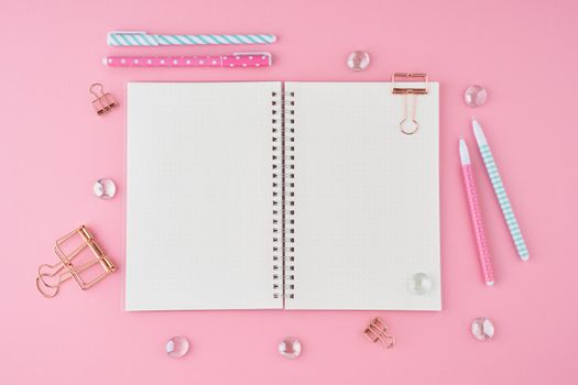 Blank notepad page in bullet journal on bright pink office desktop. Top view of modern bright table with notebook, stationery. Mock up, copy space, concept for diary, top view