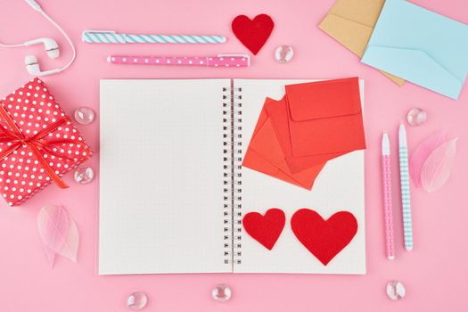 The concept of writing note, letters for Valentine's Day. Notepad blank page in bullet journal on bright pink office desktop. Top view of modern table with notebook. Mock up, copy space