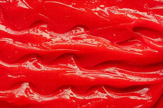 Red gel texture. Cosmetic clear liquid cream smudge. Skin care product sample closeup. Toothpaste or wax background