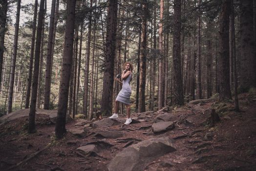 Slavic tanned fair-haired young girl with a boater hat on nature. Traveler tourist in a dark forest. constant tone of clothes. dark brown background