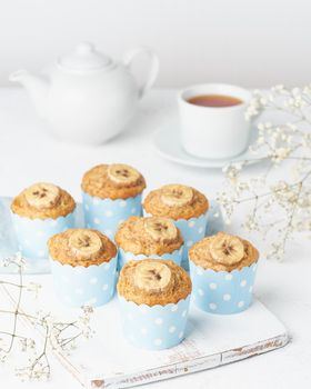 Banana muffin, cupcakes in a blue cake cases paper, side view, vertical, white concrete table