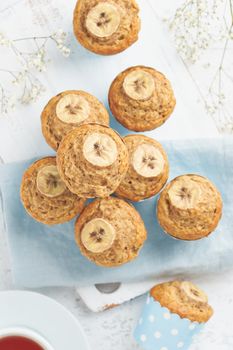 Banana muffin, top view, close up, vertical. Morning breakfast on a blue napkin, white concrete table