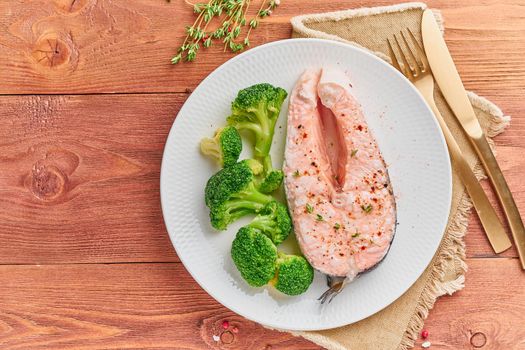 Steam salmon and vegetables, paleo, keto, fodmap diet. White plate on a rustic wooden table, top view, copy space