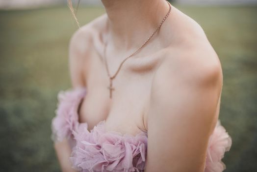 Young slim girl in elegant evening pink festive dress stands on the green background