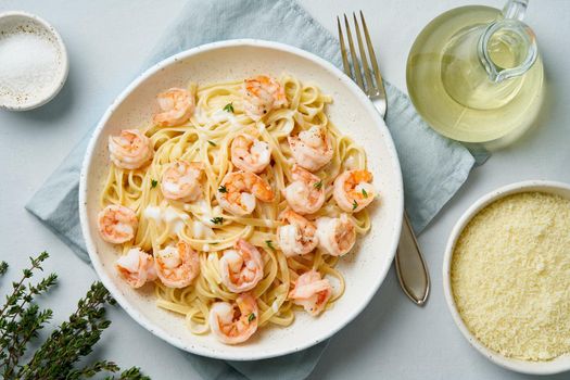 Pasta bavette with fried shrimps, bechamel sauce, thyme on blue table, top view, italian cuisine.