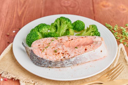 Steam salmon and vegetables, paleo, keto, fodmap diet. White plate on a rustic wooden table, side view