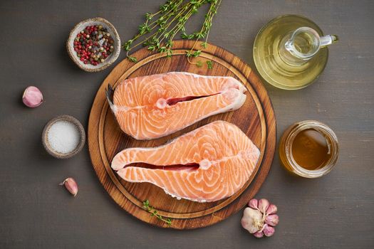 Two salmon steaks, top view, close up. Fish fillet, large sliced portions on chopping board on brown table.