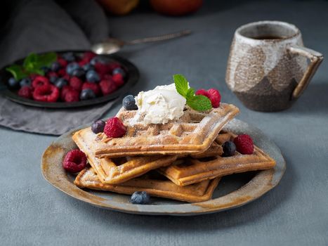 Belgian waffles with raspberries, chocolate syrup. Breakfast with tea on dark background, side view