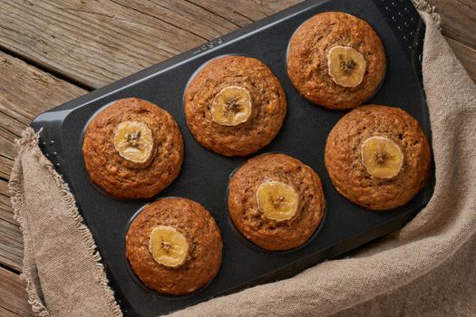 Banana muffin in tray, top view. Cupcakes on old linen napkin, rustic wooden table, breakfast with cake