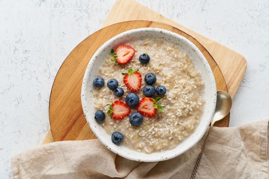 Oatmeal rustic porridge with blueberry, bilberry, blackberry, strawberry, dash diet, wooden white background top view copy space