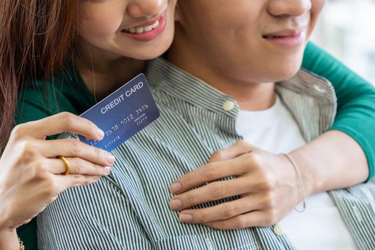 Young couple use credit card for online shopping on internet website at home. Number on the credit card is mock up. No personal information shown on the credit card. Online business shopping concept.
