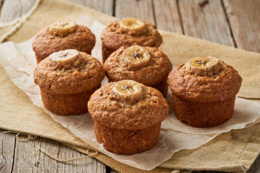 Banana muffin, side view. Cupcakes on old linen napkin, rustic wooden table, a breakfast with cake