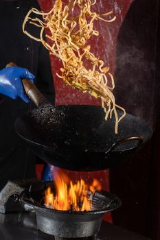 Flying noodles for wok box with meat, soy sauce fried in a wok pan, street food.