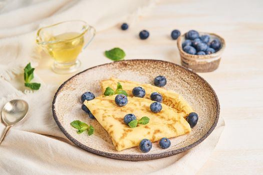 Two pancakes with blueberries and mint on plate, side view