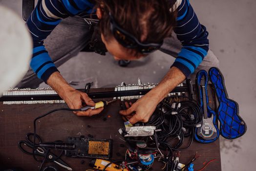 Industrial worker man soldering cables of manufacturing equipment in a factory. Selective focus. High-quality photo