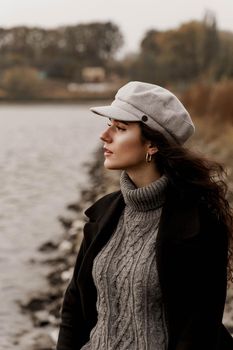 Attractive girl tourist travels around her country. Young woman with curly hair looks at the lake and dreams about her life