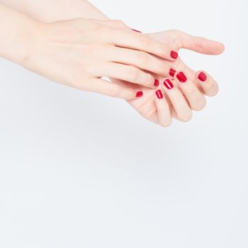 young female hands with beautiful red nail polish with gloss shine, skincare for hands, spa therapy for women, copy space white background