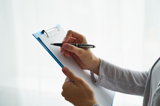woman holding clipboard and writing on it, concept of work with documents and information
