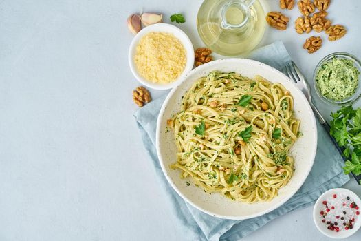 Pesto pasta, bavette with walnuts, parsley, garlic, nuts, olive oil. Top view, copy space, blue background.