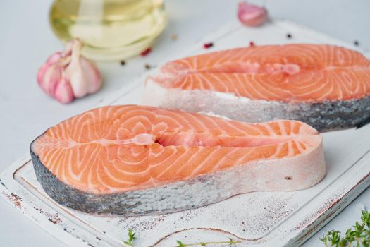 Two raw salmon steaks, fish fillet, large sliced portions on chopping board on table. Food background