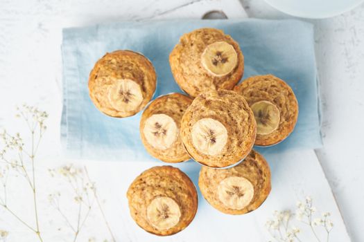 Banana muffin, top view, close up. Morning breakfast on a blue napkin, white concrete table