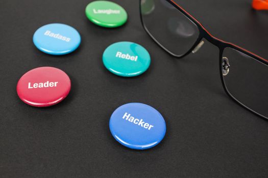 Colored plastic magnetic buttons on a black background next to glasses.