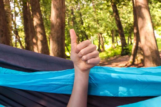 Cheerful hand in a hammock at the forest. outdoor travel concept image.