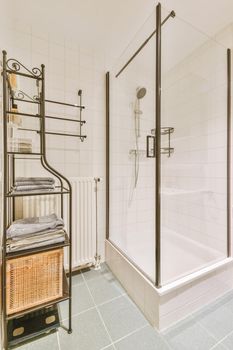 The interior of a bathroom with a glazed shower and shelves for towels in a modern apartment