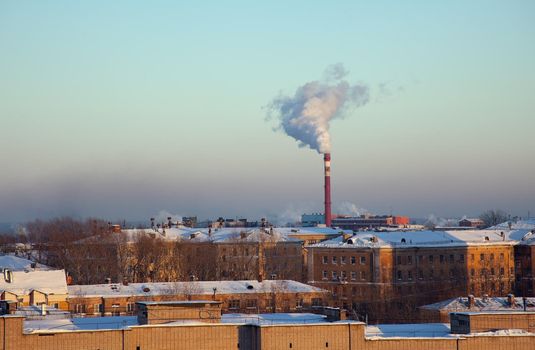 Winter city with roof under snow and pipe with smoke