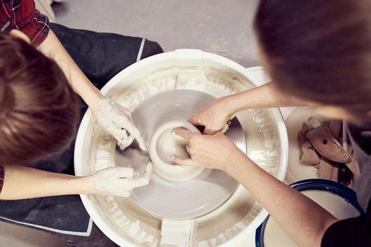 Women making ceramic pottery, concept for a workshop and master class, four hands close-up, focus on potters, palms with pottery. Two woman. Creative hobby concept, side hustle. Top view